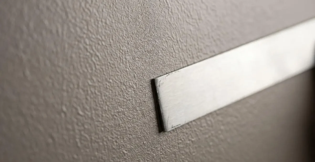 Examen minutieux des finitions murales sur chantier BTP avec règle de mesure pour vérification des tolérances DTU
